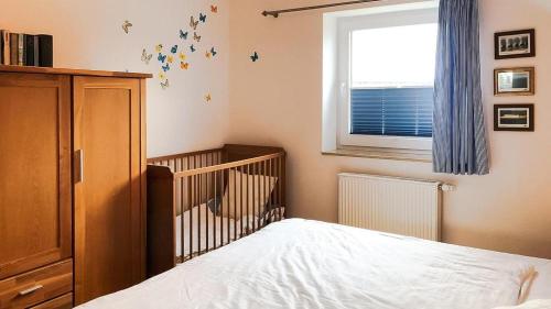 博恩Haus Alte Bäckerei - Boddenblick的一间卧室设有一张婴儿床和一扇窗户。
