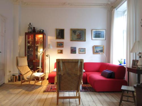 哥本哈根ApartmentInCopenhagen Apartment 931的客厅配有红色的沙发和椅子