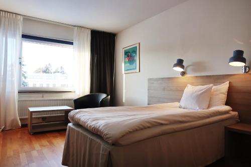 诺尔泰利耶Optima Hotel Roslagen by Reikartz的配有一张床、一张书桌和一扇窗户的酒店客房