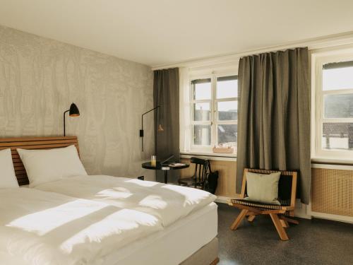 巴塞尔Boutique & Design Hotel Volkshaus Basel的一间卧室配有一张床、一把椅子和窗户。