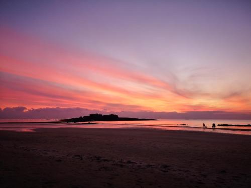 普洛埃默L'horizon - Bord de mer的两人在日落时分在海滩上散步