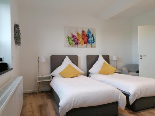 诺伊斯Gästezimmer Bergerhof - Ankommen und Wohlfühlen的配有白色墙壁和黄色枕头的客房内的两张床