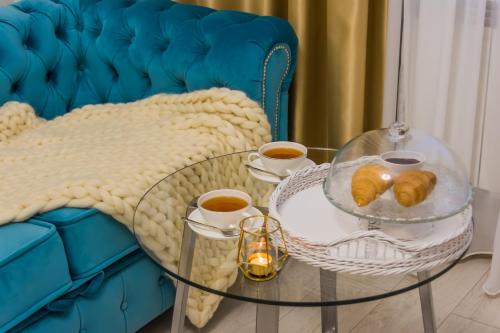 彼尔姆Versal Hotel Perm的蓝色的沙发,配有玻璃桌和糕点