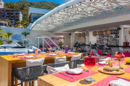 巴亚尔塔港阿尔玛豪华度假村 - LGBT海滩体验的一个带桌椅的用餐室和一个游泳池