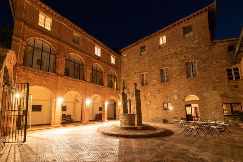 圣罗科阿费力Borgo San Lorenzo a Linari的一座大型砖砌建筑,晚上有庭院