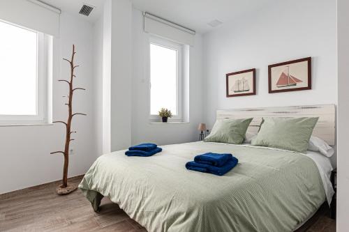科尼尔-德拉弗龙特拉Apartamentos Wamba的白色卧室配有一张大床,上面有蓝色的毛巾