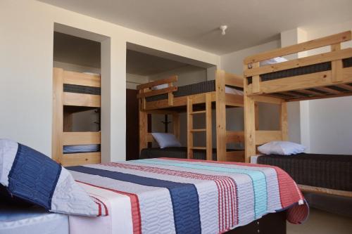 帕拉卡斯Hotel Munay的一间卧室配有双层床和一张带条纹毯子的床。