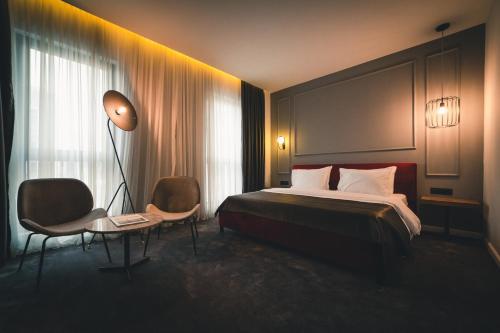 波德戈里察Boscovich Boutique Hotel的酒店客房,配有床、灯和椅子
