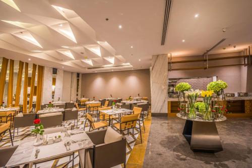 利雅德Grand Plaza Hotel - KAFD Riyadh的一间带桌椅和鲜花的用餐室