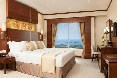 迪拜卡尔顿市中心酒店（原迪拜华威酒店）的一间卧室配有一张大床、一张桌子和一个窗户。