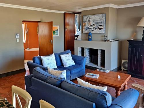 干斯拜Walkerbay Accommodation的客厅配有2张蓝色沙发和壁炉