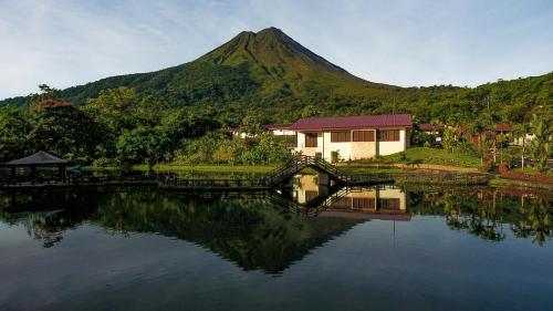 福尔图纳Los Lagos Spa & Thermal Resort Experience的水面上的房子,山底下