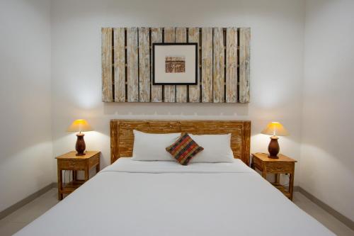 沙努尔Bali Komang Guest House Sanur的一间卧室配有一张带两盏灯的大型白色床。