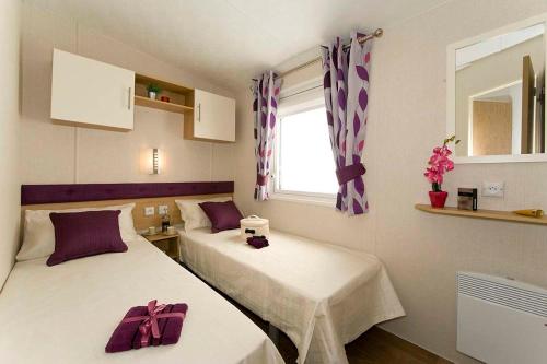 EstangCamping Les Lacs de Courtès的配有紫色弓的小客房内的两张床
