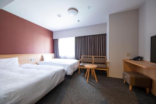 长崎Dormy Inn Premium Nagasaki Ekimae的酒店客房配有两张床和一张书桌