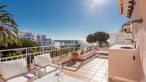 马贝拉Ático de 2 dormitorios en Andalucía del mar的阳台配有白色椅子,享有海景。
