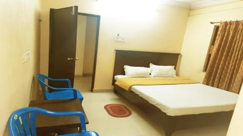 瓦朗加尔Vishnu Residency Warangal的小房间设有一张床和两把蓝色椅子