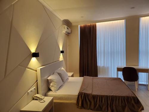 费尔干纳Tantana Hotel的酒店客房配有一张床铺、一张桌子和一张书桌。