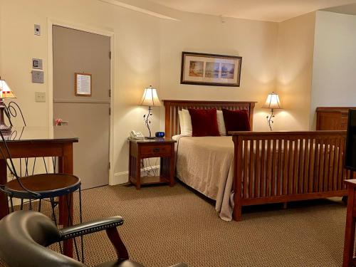 波士顿绿洲宾馆的一间卧室配有一张床、一张桌子和一把椅子