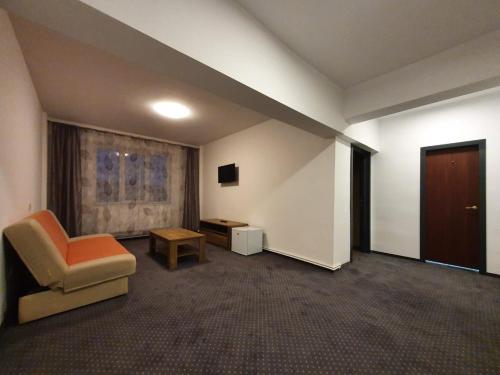 彼得罗沙尼Hotel Petroshani srl的一间带椅子和桌子的房间以及一扇门