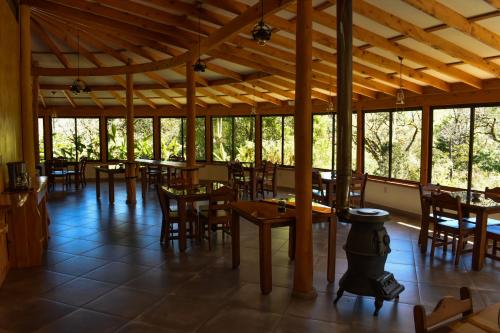 CopeyEl Toucanet Lodge的餐厅设有木桌、椅子和窗户。