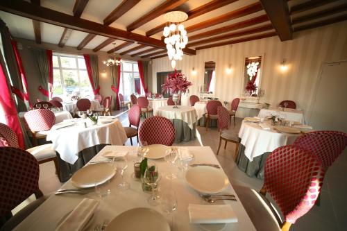 圣伊莱尔迪阿尔库厄勒里翁德奥尔酒店餐厅的用餐室配有白色的桌子和红色的椅子