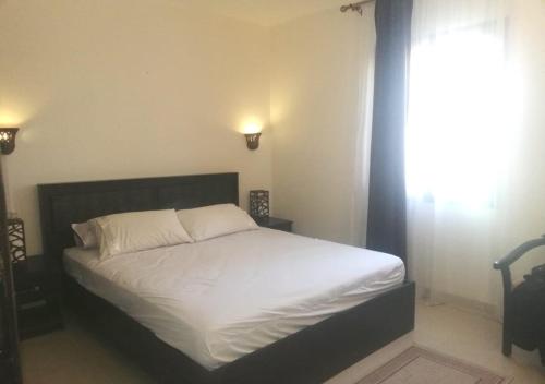 赫尔格达Chalet at Stella Makadi Beach的一间卧室配有一张带白色床单的床和一扇窗户。