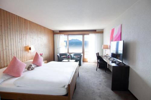 贝阿滕贝格Hotel Gloria的酒店客房配有一张床、一张书桌和一台电视。