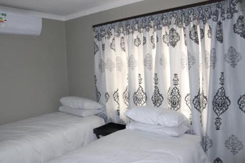 约翰内斯堡Tlelakufuma Guest House的一间卧室配有两张床和窗帘