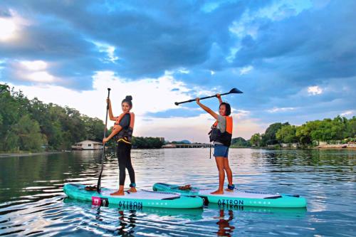 北碧Good Times Resort Kanchanaburi的两个女人站在水面上的桨板上