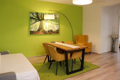莱斯诺夫Apartamente Bucegi的一间拥有绿色墙壁和桌椅的用餐室