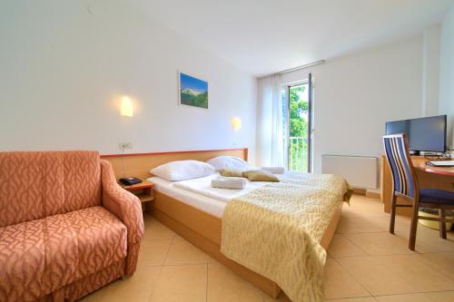 克尔克Villa Lovorka - Hotel Resort Dražica的酒店客房配有一张床、一把椅子和一张书桌