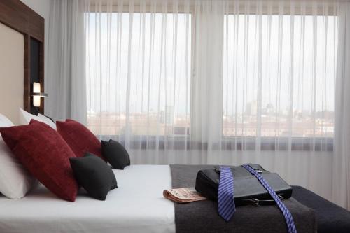 马德里Hotel Princesa Plaza Madrid的一间卧室配有一张带红色枕头的床和一扇窗户