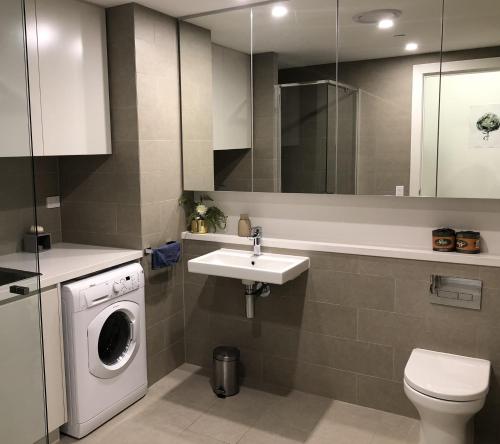 悉尼Parkview Modern Apartment w Parking @ Olympic Park的一间带洗衣机和水槽的浴室