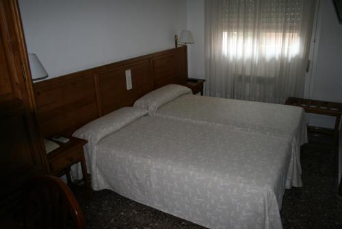 萨拉戈萨普恩特德彼德拉旅馆的卧室配有带白色棉被的床