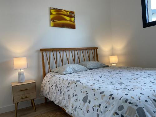 米米藏Villa L'espourguit proche de l'océan et de la forêt的一间卧室配有一张带两盏灯的床。