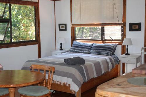克拉格斯Treehouse Cottage的卧室配有床、桌子和窗户。