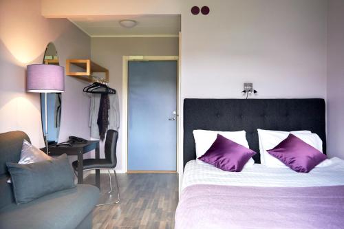 Surte速特酒店的一间卧室配有一张带紫色枕头的床和一张书桌