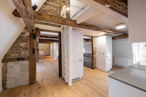 吕讷堡Johannis Suite - Schrangen-Suites-1389的阁楼厨房设有木梁和白色的墙壁。