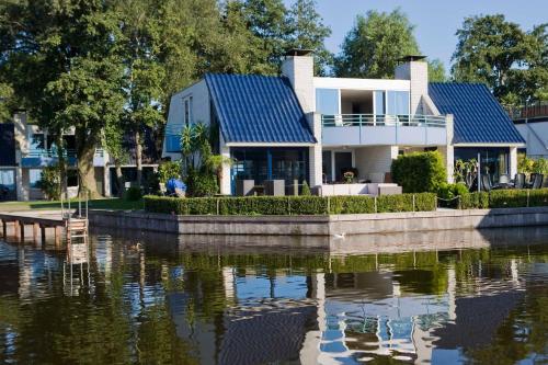 洛斯德雷赫特阿姆斯特丹/鲁斯德雷奇璃园范登布如科村度假屋的水体旁有蓝色屋顶的房子