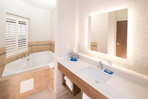 贝城贝城快捷假日&套房酒店的带浴缸、水槽和镜子的浴室