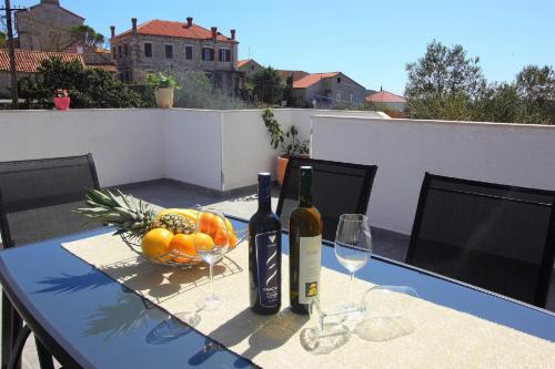西利皮Apartment Milenka的一张桌子,上面放着两瓶葡萄酒和一碗水果