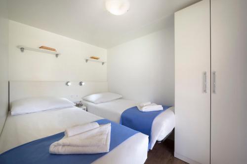 罗维尼Maistra Camping Polari Mobile homes的白色墙壁客房的两张床