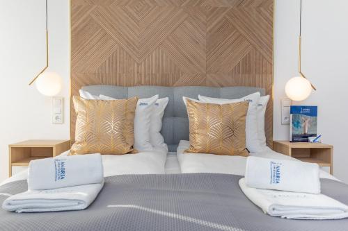 斯维诺乌伊希切Ambria Apartments Dębina的一张带白色枕头和木制床头板的床