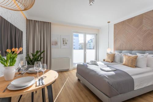 斯维诺乌伊希切Ambria Apartments Dębina的一间卧室配有一张大床和一张带酒杯的桌子。