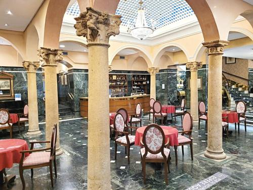巴利亚多利德Hotel Imperial的大楼内一家餐厅,配有红色的桌椅