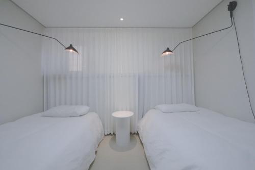 首尔Lovely House Hongdae的配有2张床的白色墙壁和灯