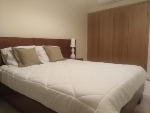 阿尔曼萨Almancil Park Apartment的卧室配有一张白色大床和木制床头板