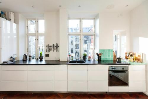 哥本哈根ApartmentInCopenhagen Apartment 1357的厨房配有白色橱柜和黑色台面
