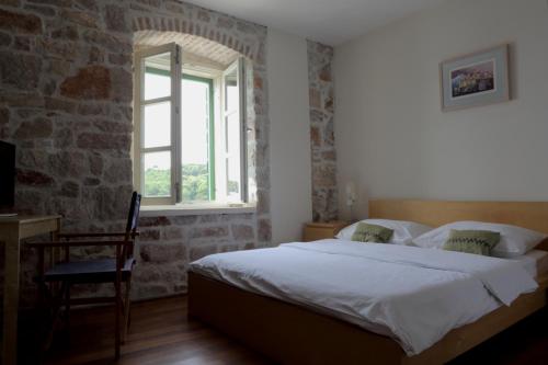 普尔维奇卢卡Hotel Maestral的一间卧室设有一张床、一个窗口和一把椅子